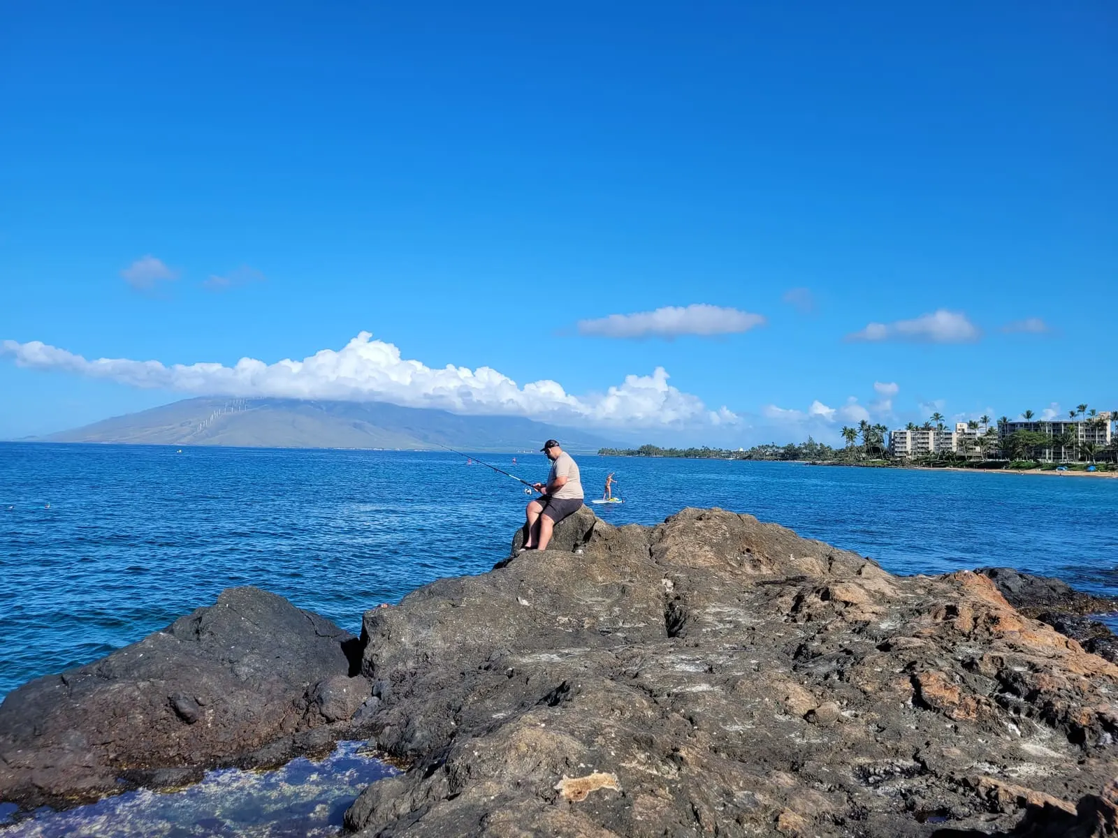 Rocky coastline looking across blue water toward distant mountains