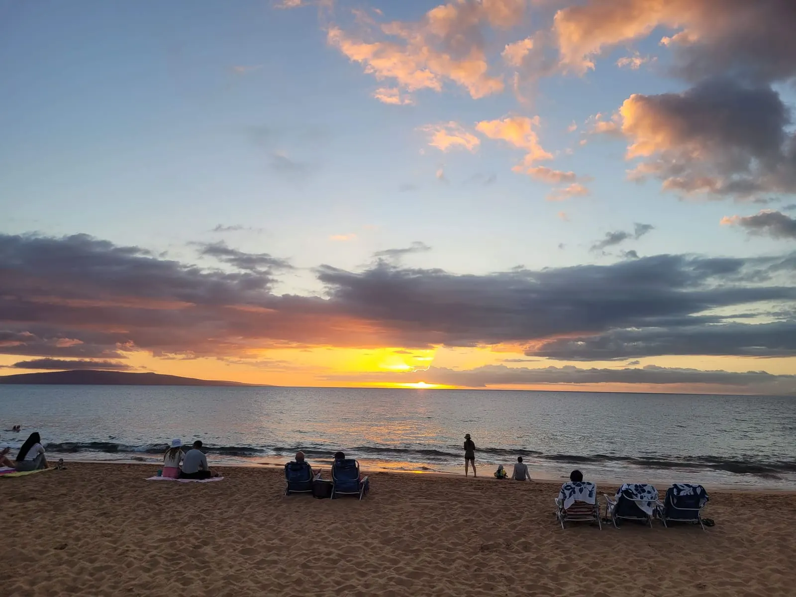 Beach chairs facing a colorful ocean sunset