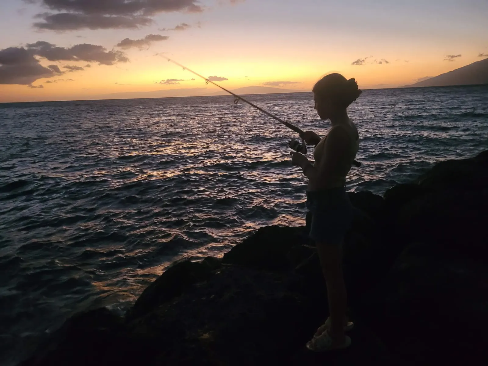 Fishing from rocks at sunset